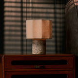 Bonnard cordless table lamp in Silver Travertine stone glowing on a teak sideboard at dusk, sofa in the backdrop