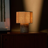 Bonnard cordless table lamp in Silver Travertine stone glowing warmly on a teak sideboard beside framed wall art