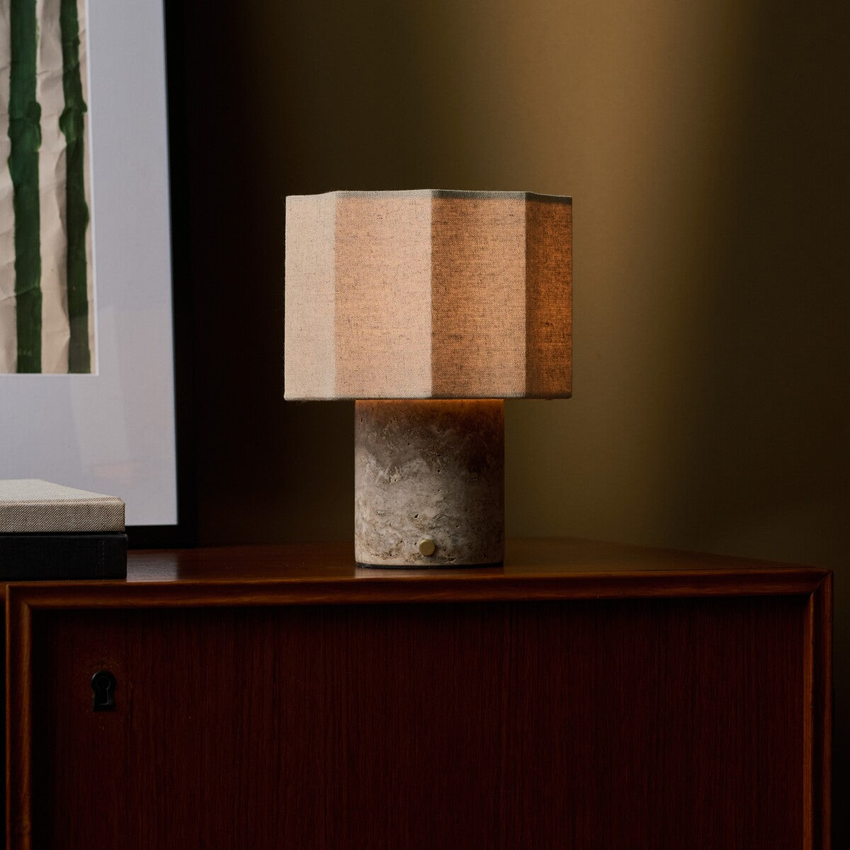 Bonnard rechargeable table lamp in Silver Travertine stone on a teak sideboard beside green striped wall art