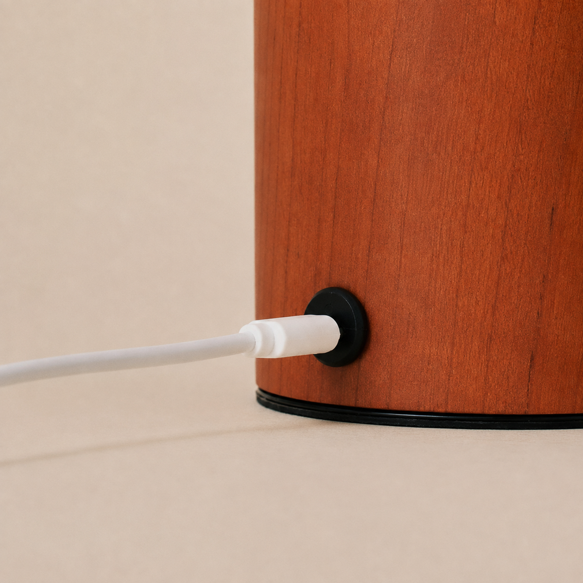 Magnetic charging cable connecting to the chestnut wood base of the Aurora rechargeable lamp