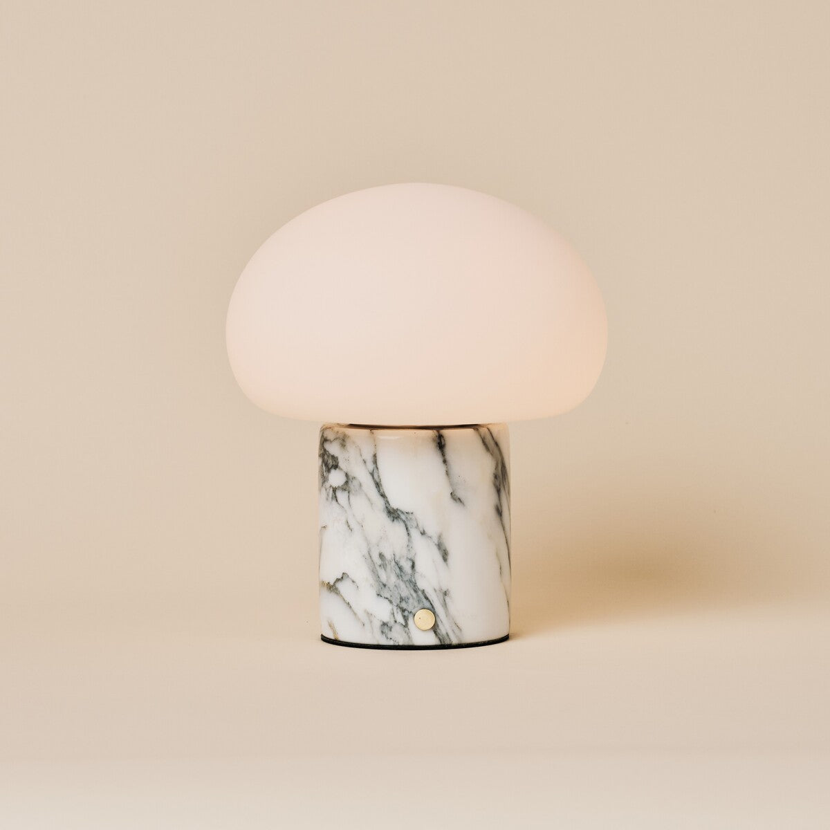 Rechargeable table lamp with a dome shade on an Arabescato marble base with grey veining, studio shot