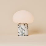 Rechargeable table lamp with a dome shade on an Arabescato marble base with grey veining, studio shot