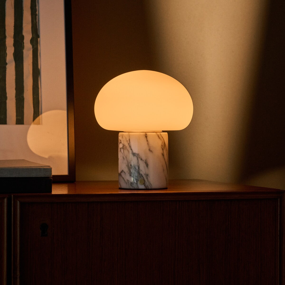 Tavellio cordless table lamp with an Arabescato marble base glowing softly on a credenza at dusk