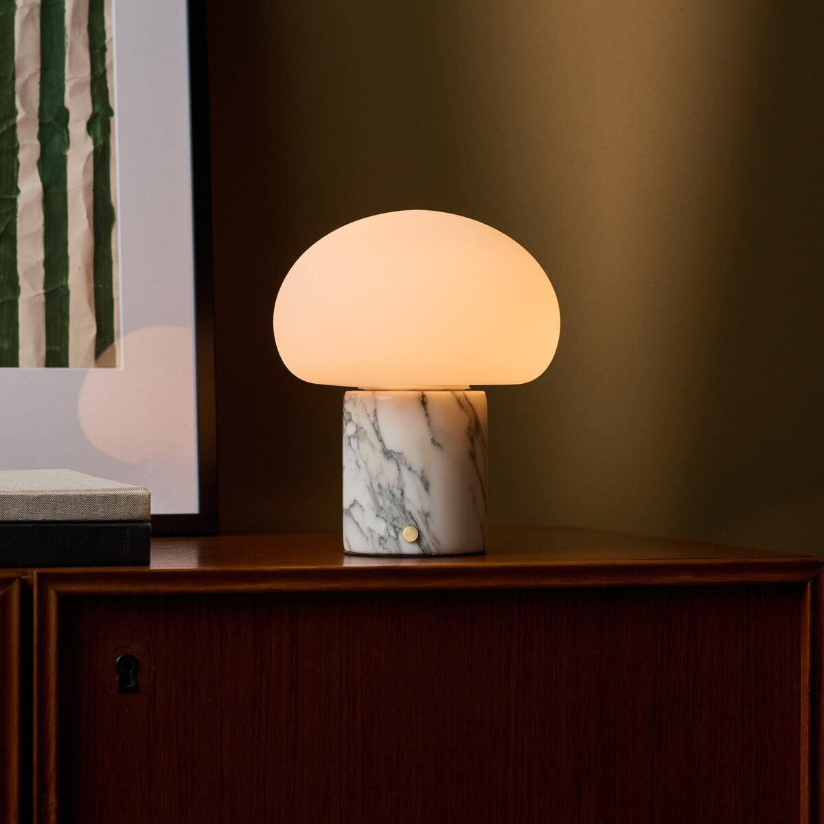 Rechargeable table lamp with an Arabescato marble base lit on a walnut sideboard beside abstract wall art