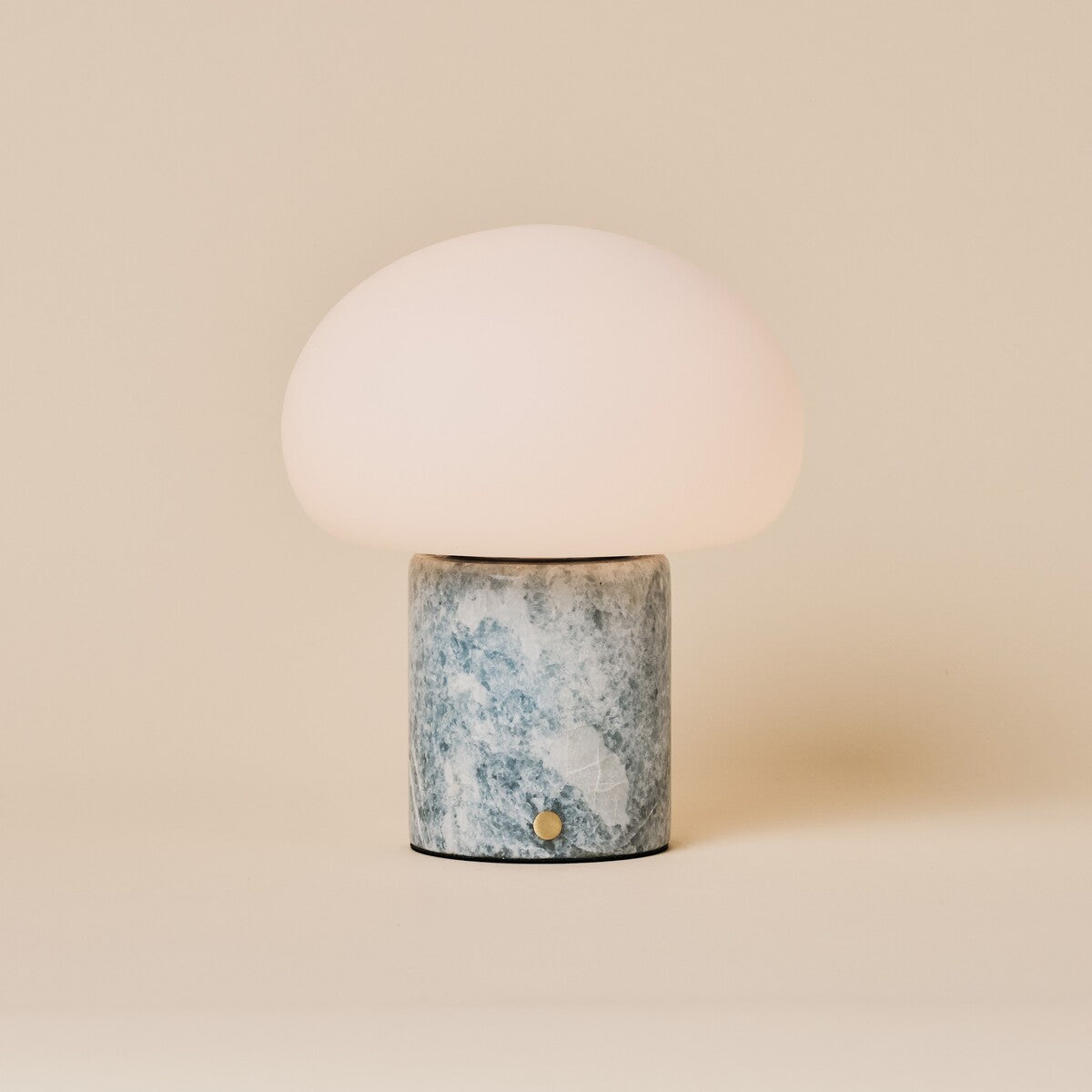 Rechargeable table lamp with blue calcite marble base and opal glass dome shade on a plain backdrop
