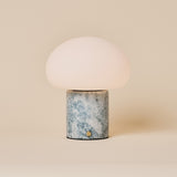 Codde Blue Calcite marbre lampe de table sans fil Tavellio – photo studio sur fond beige – dôme arrondi en verre opalin blanc