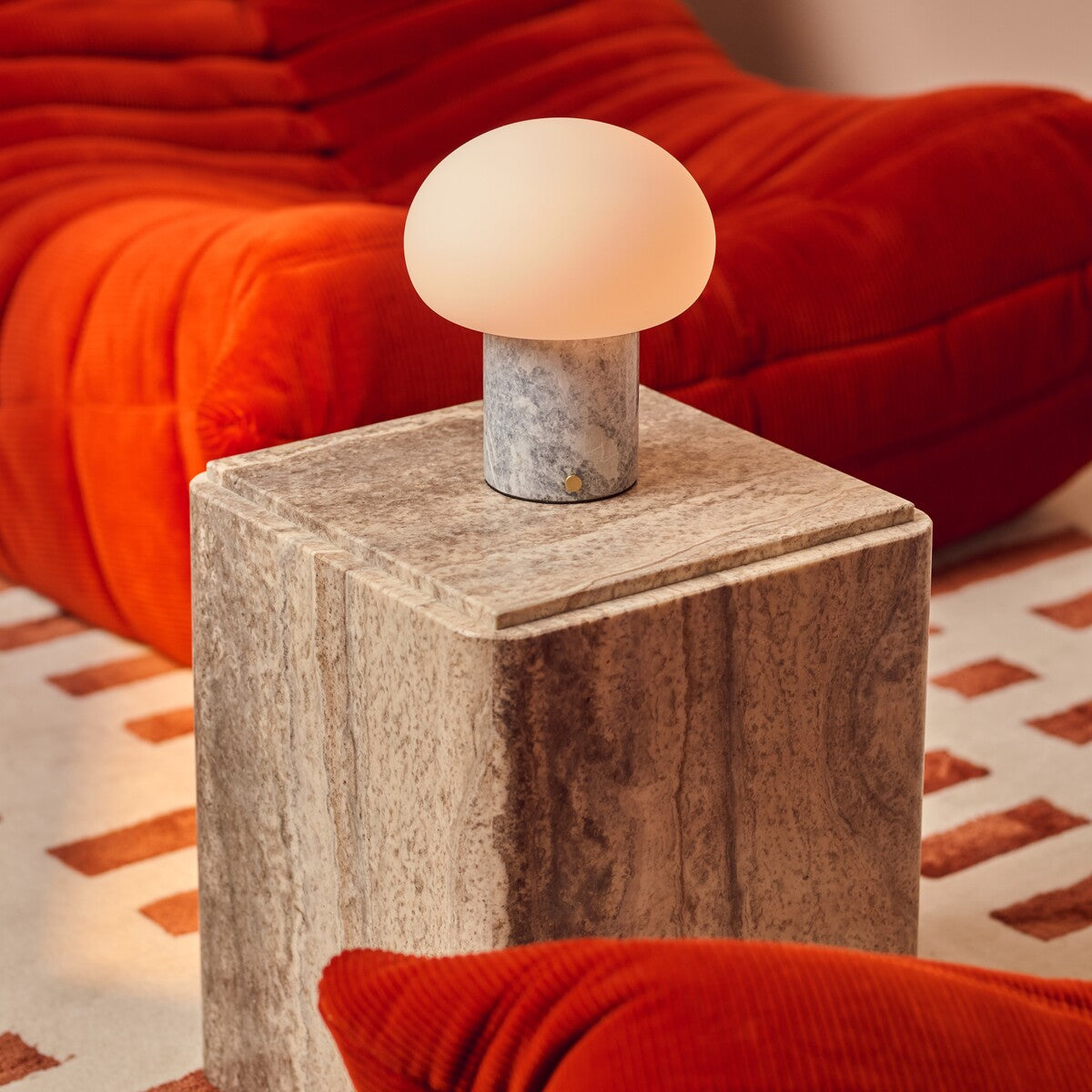 Codde Blue Calcite marbre lampe de table rechargeable Tavellio – posée sur un cube en pierre à côté d un canapé orange brûlé
