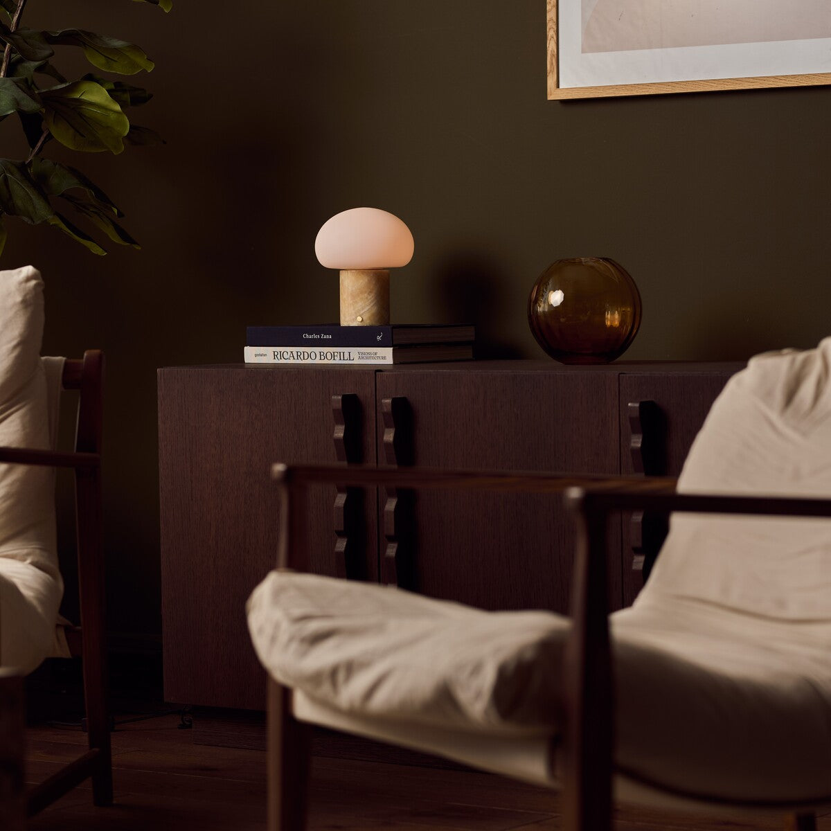 Cordless table lamp with honey onyx marble base glowing on a dark wood sideboard beside an amber glass vase