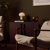 Cordless table lamp with honey onyx marble base glowing on a dark wood sideboard beside an amber glass vase