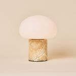 Rechargeable table lamp with honey onyx marble base and opal glass dome shade on a plain backdrop