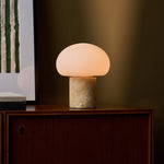 Cordless table lamp with honey onyx marble base glowing on a wooden cabinet beneath a striped green artwork