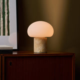 Cordless table lamp with honey onyx marble base glowing on a wooden cabinet beneath a striped green artwork