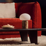 Coddé Large marbre Emperador foncé lampe de table rechargeable Tavellio – table basse noire devant un canapé en velours rouge – coupelle en travertin