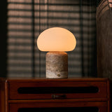 Coddé Large travertin gris lampe de table rechargeable Tavellio – commode en bois foncé devant des stores vénitiens – fauteuil rayé gris-brun visible