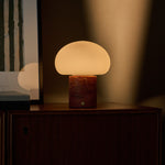 Cordless table lamp with red travertine base glowing on a wooden cabinet beneath a striped green artwork