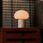 Coddé Rosa Aurora marbre rose lampe de table sans fil Tavellio – sur une commode – ombres rayées des stores projetées derrière