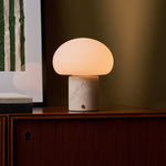 Coddé Rosa Aurora marbre rose lampe de table rechargeable Tavellio – cadrage rapproché sur le meuble – tissu à rayures visible à droite