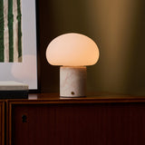 Coddé Rosa Aurora marbre rose lampe de table rechargeable Tavellio – cadrage rapproché sur le meuble – tissu à rayures visible à droite