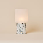 Cuyp Arabescato Marble rechargeable table lamp glowing softly on a beige studio background