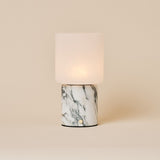 Cuyp Arabescato Marble rechargeable table lamp glowing softly on a beige studio background