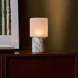 Cuyp Arabescato Marble rechargeable table lamp on a walnut cabinet beside striped artwork and stacked books