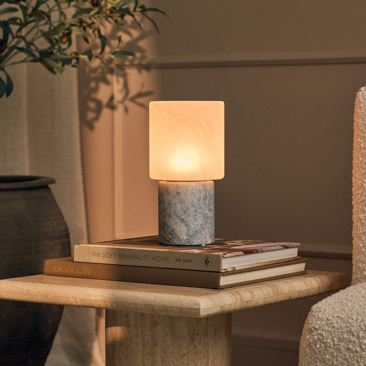 Cordless table lamp with blue calcite marble base glowing on a side table stacked with books