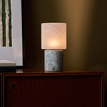 Cordless table lamp with blue calcite marble base lighting a walnut cabinet in a dim room