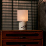 Cuyp table lamp with white marble base and square glass shade glowing warmly at bedside