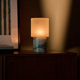 Cuyp Calacatta Vionaro marble rechargeable table lamp lit on a dark wood cabinet beside art