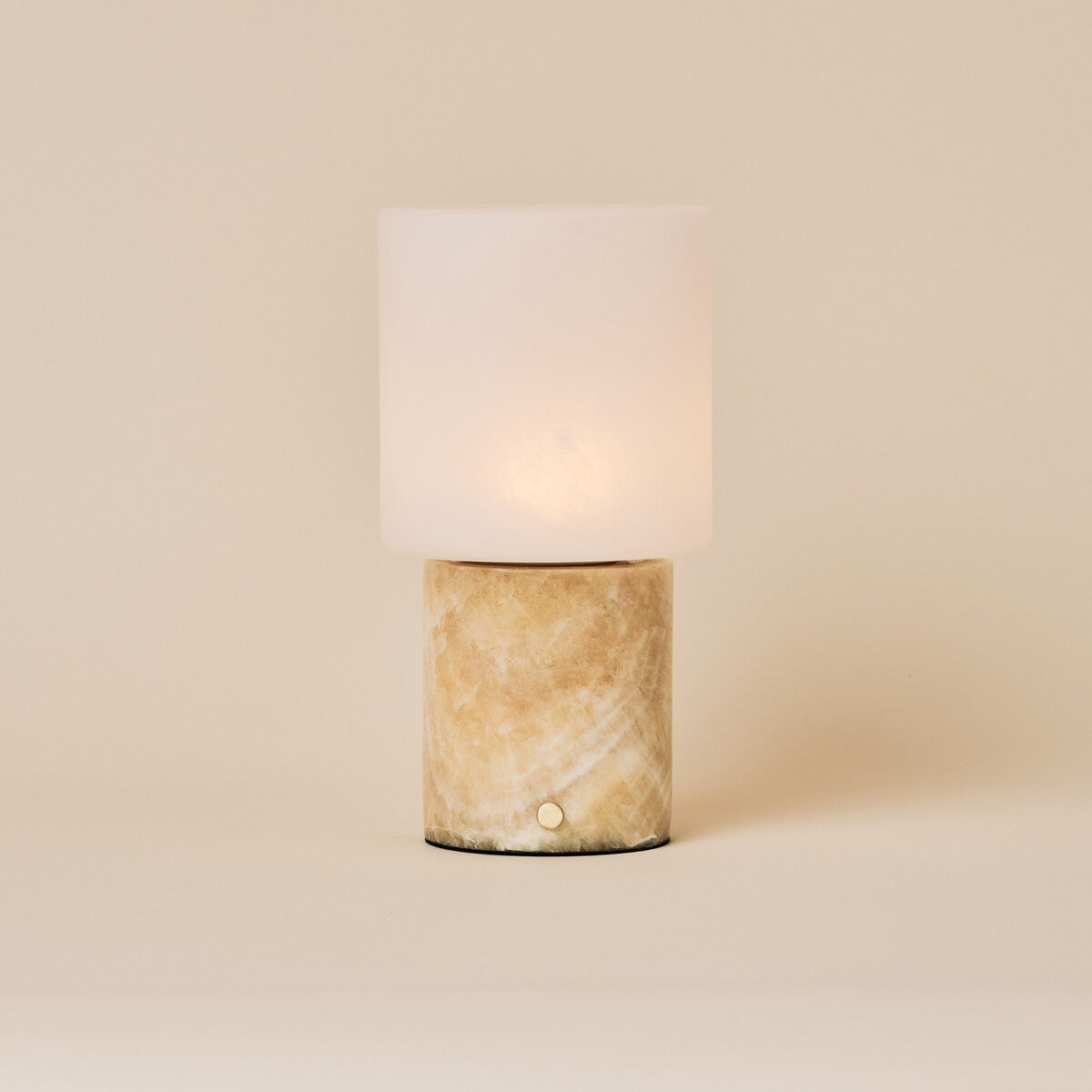 Cuyp Honey Onyx Marble Rechargeable Table Lamp glowing on a cream studio backdrop
