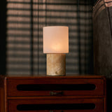 Tavellio rechargeable table lamp with honey onyx base on a nightstand under blind-cast shadows