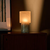 Cordless table lamp with honey onyx marble base glowing against a striped green artwork