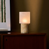 Rechargeable table lamp with honey onyx marble base glowing on a walnut cabinet at dusk