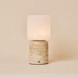 Cuyp Large rechargeable table lamp with a beige travertine base and glowing frosted glass shade