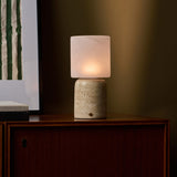 Tavellio Cuyp Large cordless table lamp glowing on a wood cabinet beside striped wall art