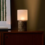 Rechargeable table lamp Cuyp Large in Emperador dark marble glowing on a wood cabinet against an olive wall