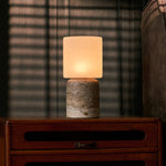 Cuyp Large rechargeable table lamp with silver travertine base glowing beside a striped sofa