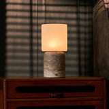 Cuyp Large rechargeable table lamp with silver travertine base glowing beside a striped sofa