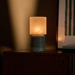 Cuyp Large cordless table lamp with silver travertine base glowing softly beside framed wall art