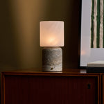 Tavellio Cuyp Large cordless table lamp glowing on a wood cabinet beside stacked books