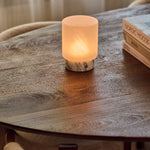 Cuyp Small cordless table lamp glowing on a round wood table beside Nordic Moods books