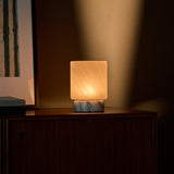 Tavellio Cuyp Small rechargeable table lamp beside a striped green print on a dark wood cabinet