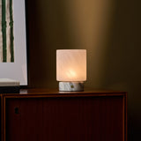 Cordless table lamp with softly veined marble base close up on a dark wood cabinet