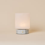 Cuyp Small cordless table lamp in Bianco Statuarietto white marble glowing on a beige studio backdrop