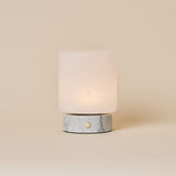 Cuyp Small cordless table lamp in Bianco Statuarietto white marble glowing on a beige studio backdrop