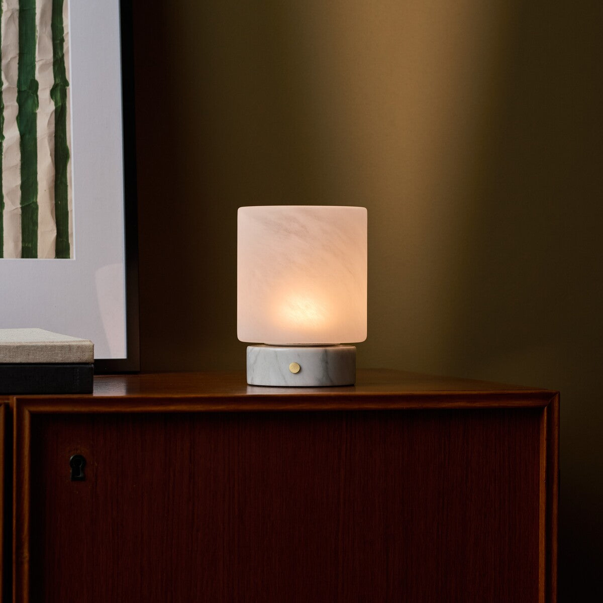Cuyp Small cordless table lamp in Bianco Statuarietto white marble on a wood cabinet against a green wall