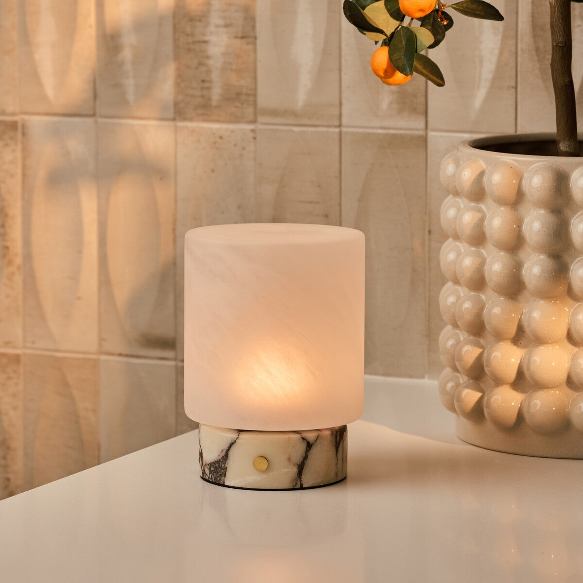 Rechargeable table lamp Cuyp Small beside a framed striped artwork on a walnut cabinet