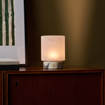 Cordless table lamp Cuyp Small, Calacatta Vionaro marble, glowing on a wood cabinet at dusk