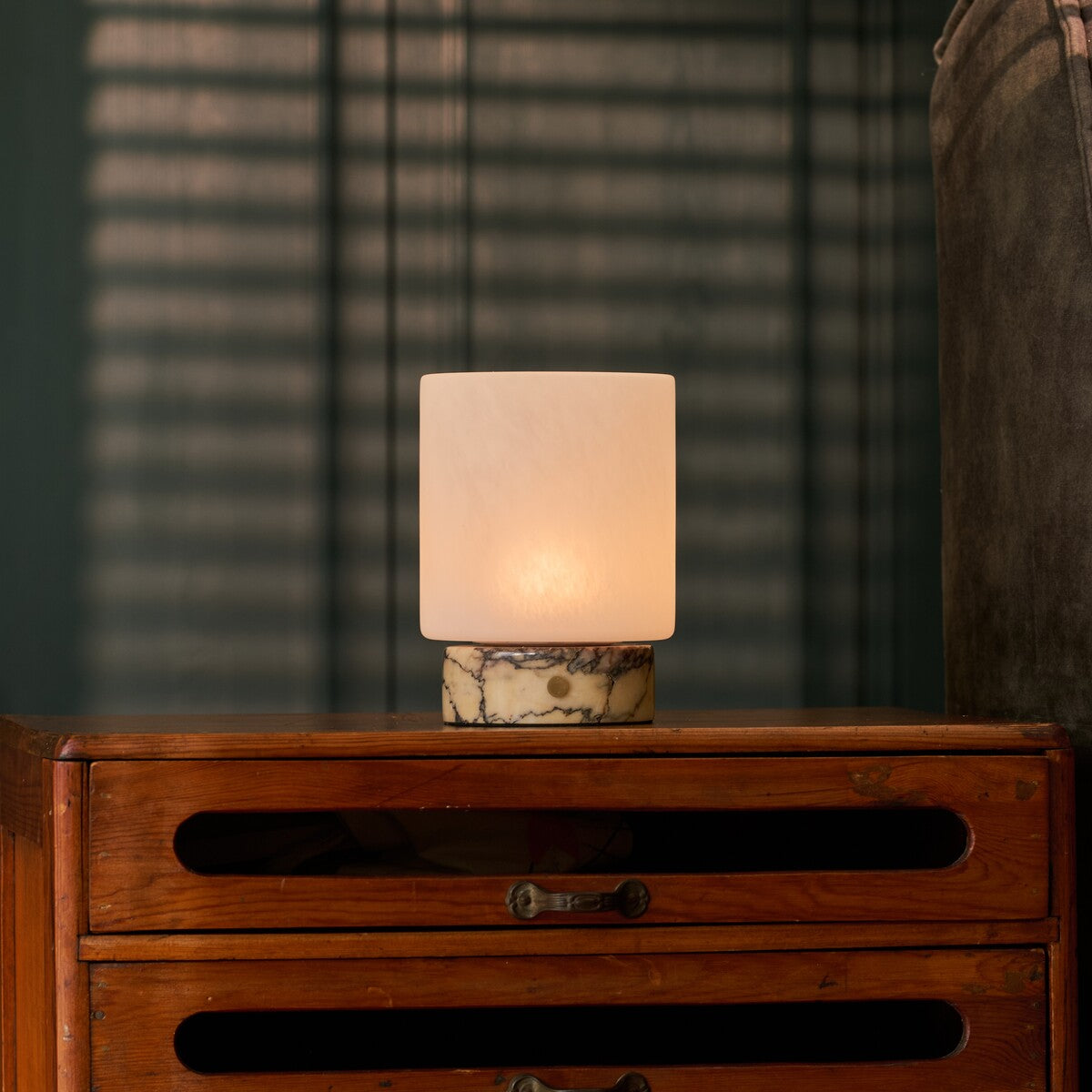 Oplaadbare tafellamp Cuyp Small in geel Calacatta Vionaro marmer op een houten kast in een sfeervol verlichte kamer