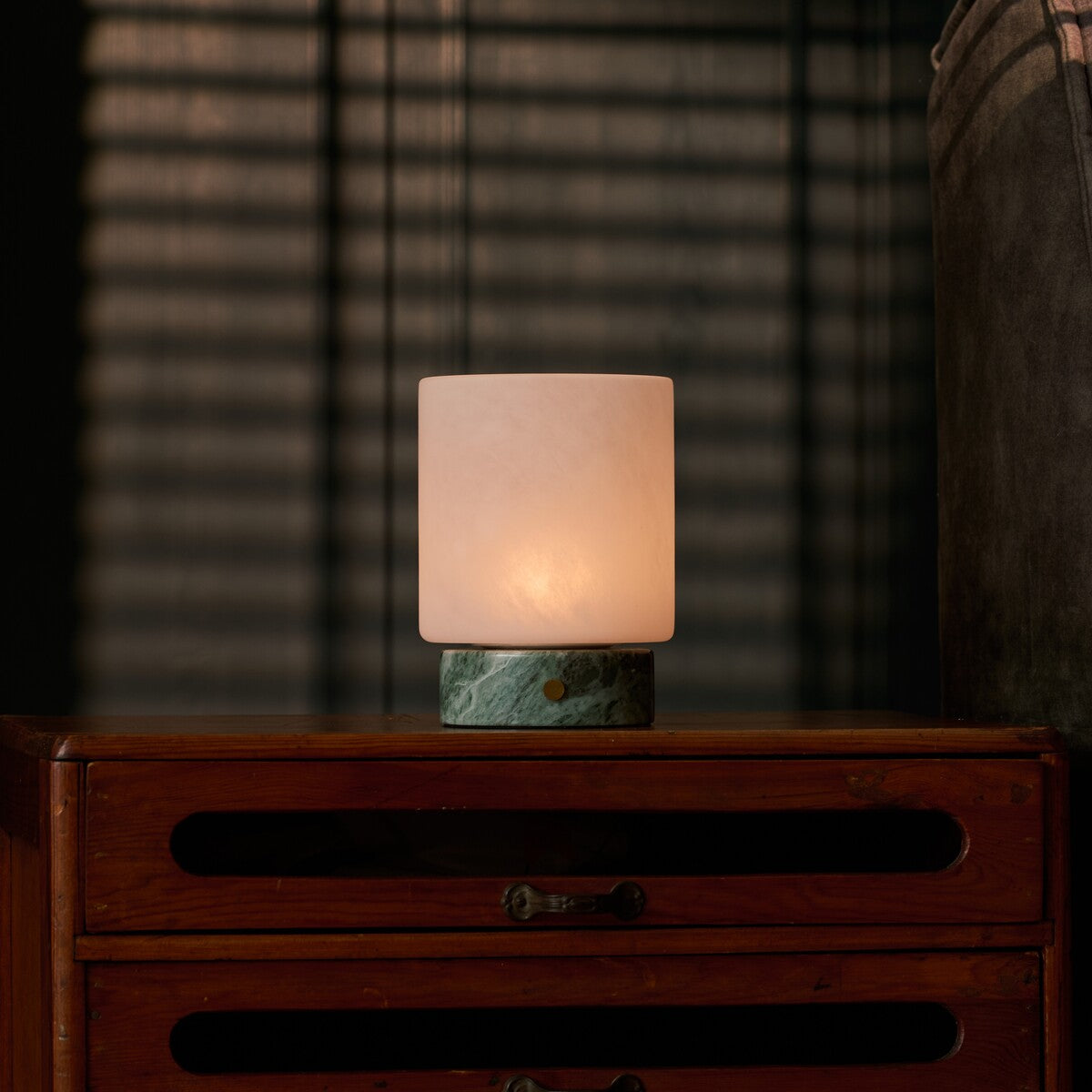 Cuyp Small rechargeable table lamp in Ice Green marble glowing on a vintage wood dresser at dusk